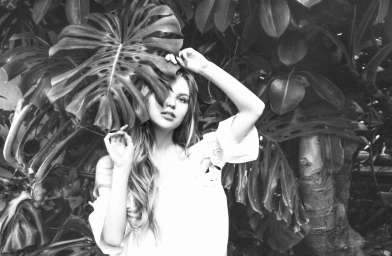 Girl covering face with Monstera Leaf - Plant Vault Rare Houseplant Retailer & Wholesaler - Encinitas CA